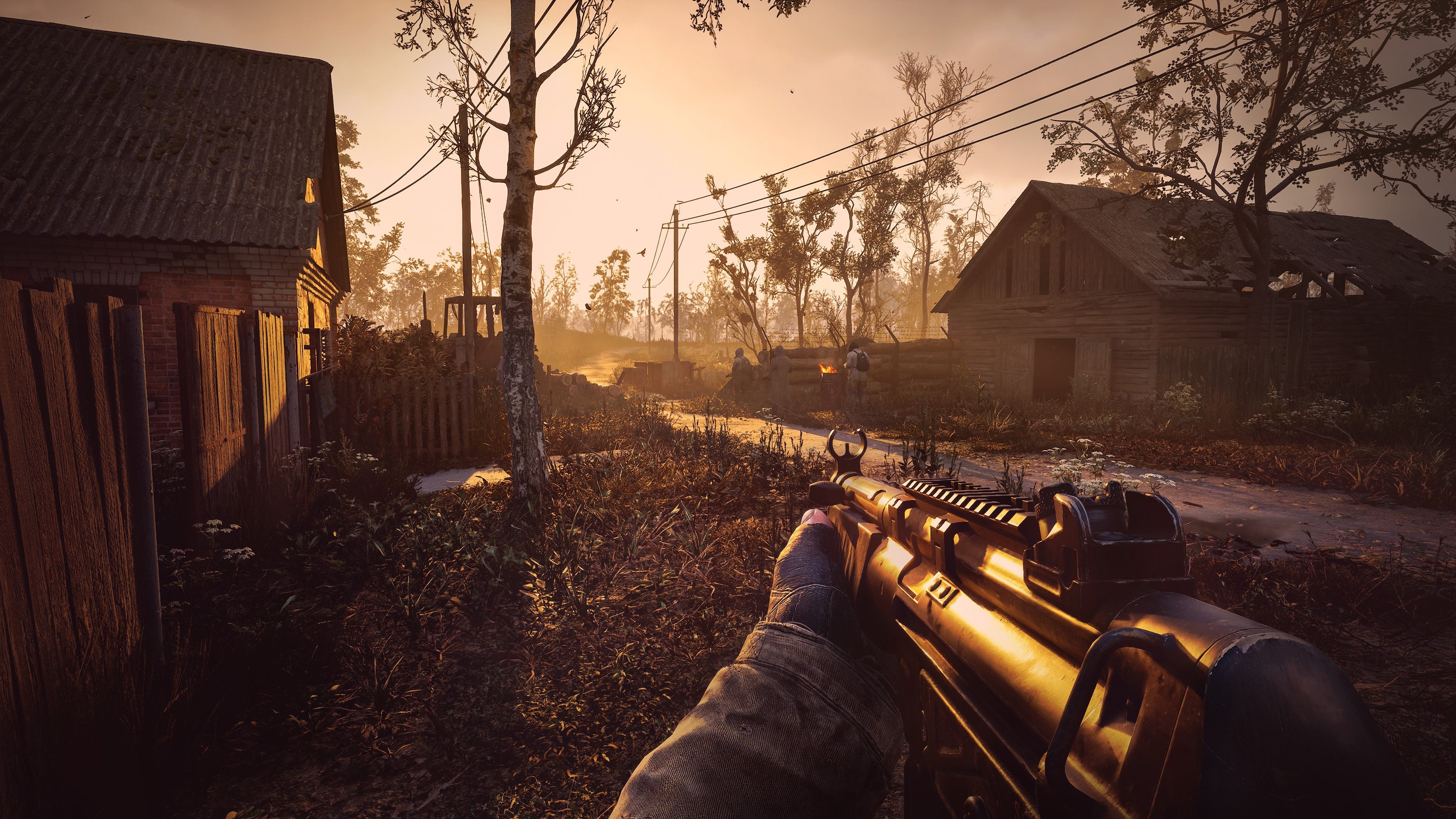 The player walks through a village at dusk with their gun raised in Stalker 2.