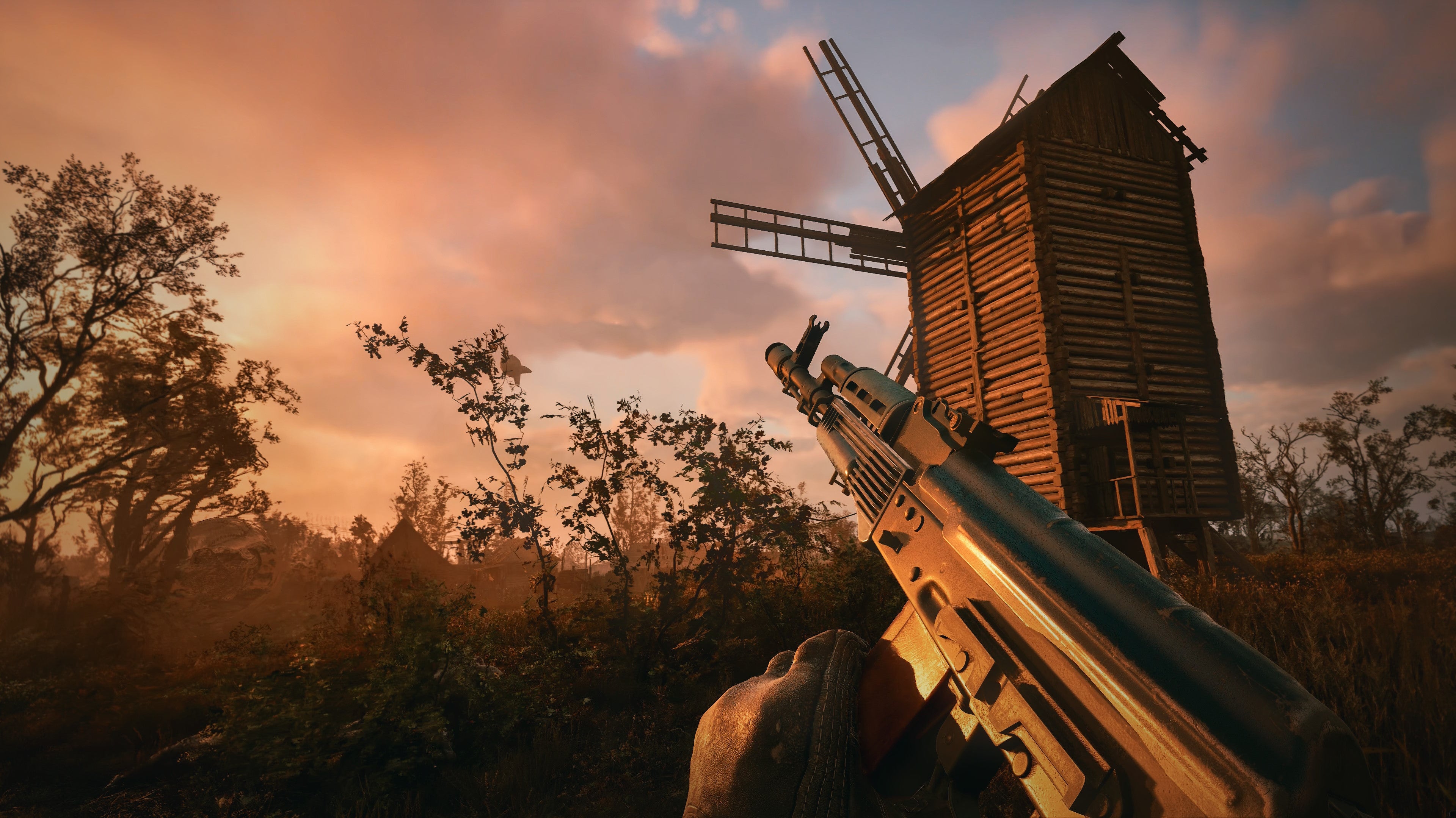 A player raises their gun toward a dusky sky near a windmill in Stalker 2