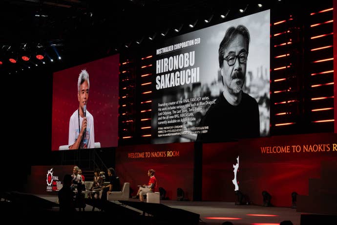 Hironobu Sakaguchi sits on a panel - a huge image of his own portrait above him - at Final Fantasy FanFest 2023.
