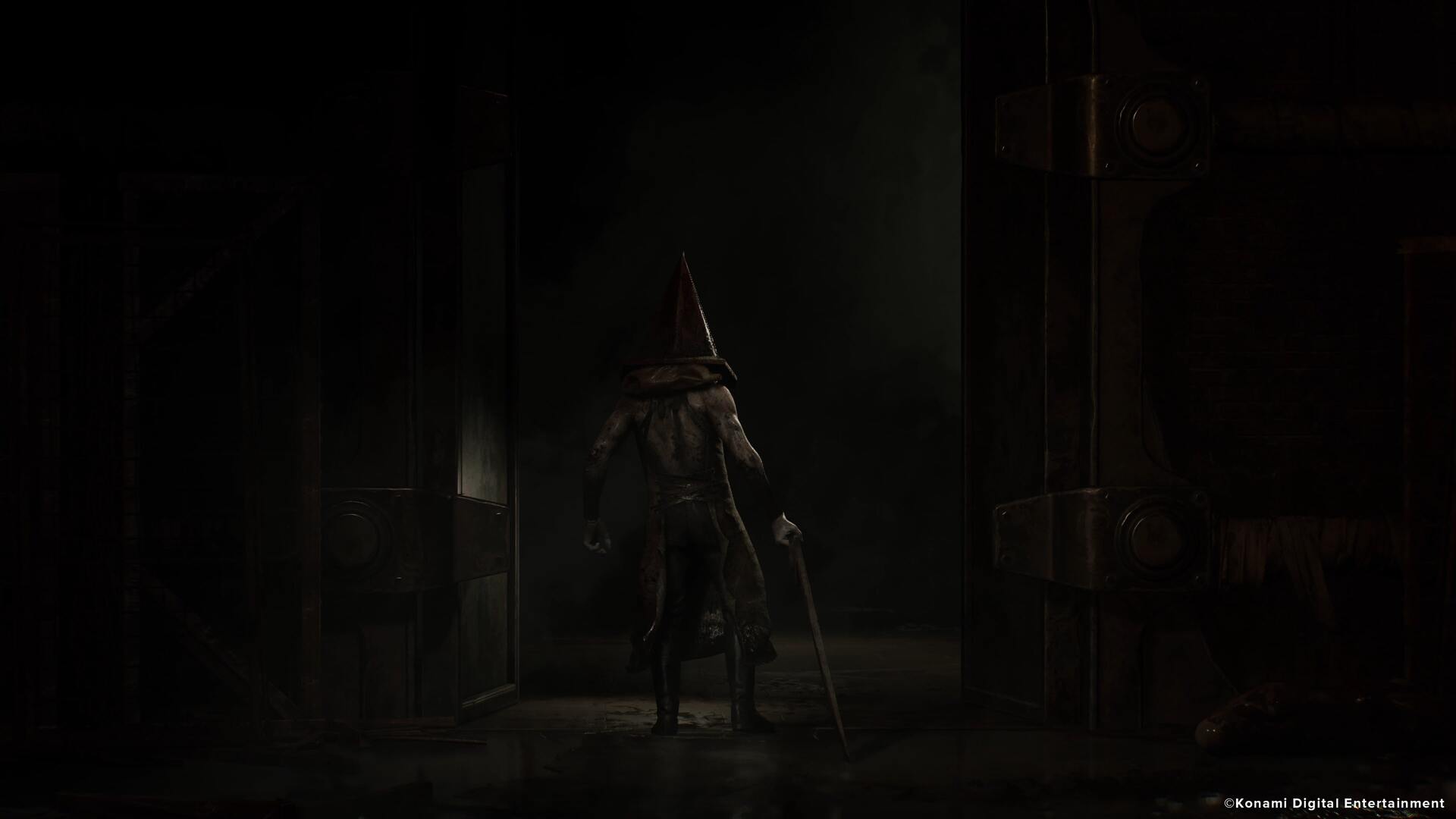 The back of Pyramid Head is seen exiting the apartments after a siren starts blaring in the Silent Hill 2 remake - 6
