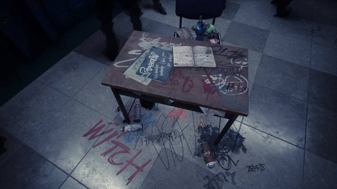 Silent Hill The Short Message Screenshot. A school desk sits in the middle of a corridor. Insults have been graffitied onto it, including the word “witch”. It’s a reminder of a similar scene from the first Silent Hill movie/game.