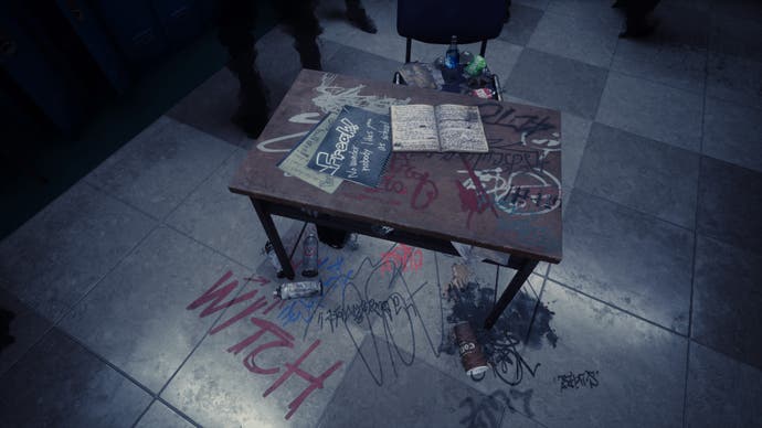 Silent Hill The Short Message Screenshot. A school desk sits in the middle of a corridor. Insults have been graffitied onto it, including the word "witch". It's a reminder of a similar scene from the first Silent Hill movie/game.