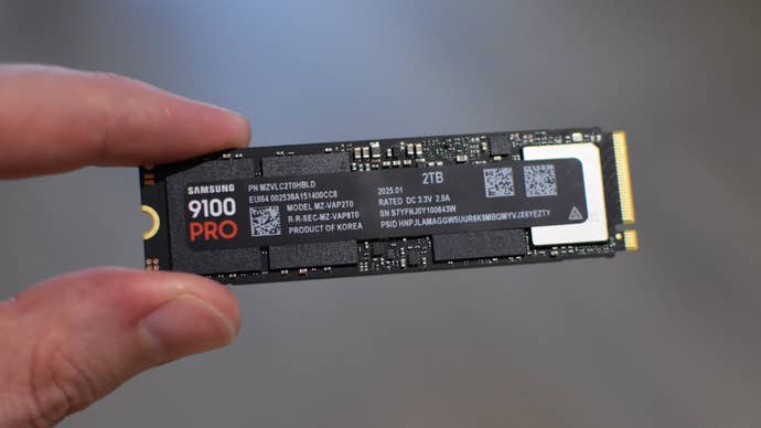The Samsung 9100 Pro SSD being held betwixt 2 fingers.
