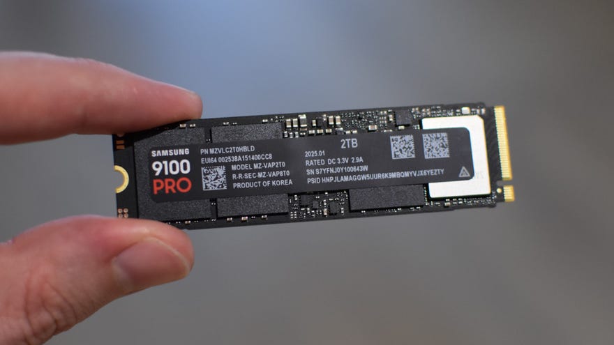 The Samsung 9100 Pro SSD being held betwixt  2  fingers.