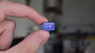 A Samsung Pro Plus microSD card being held between a finger and thumb.