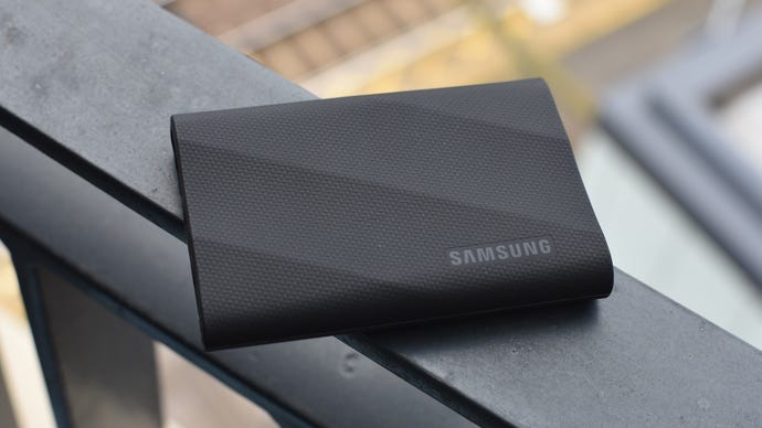The Samsung T9 external SSD, in black, on top of a flat railing.