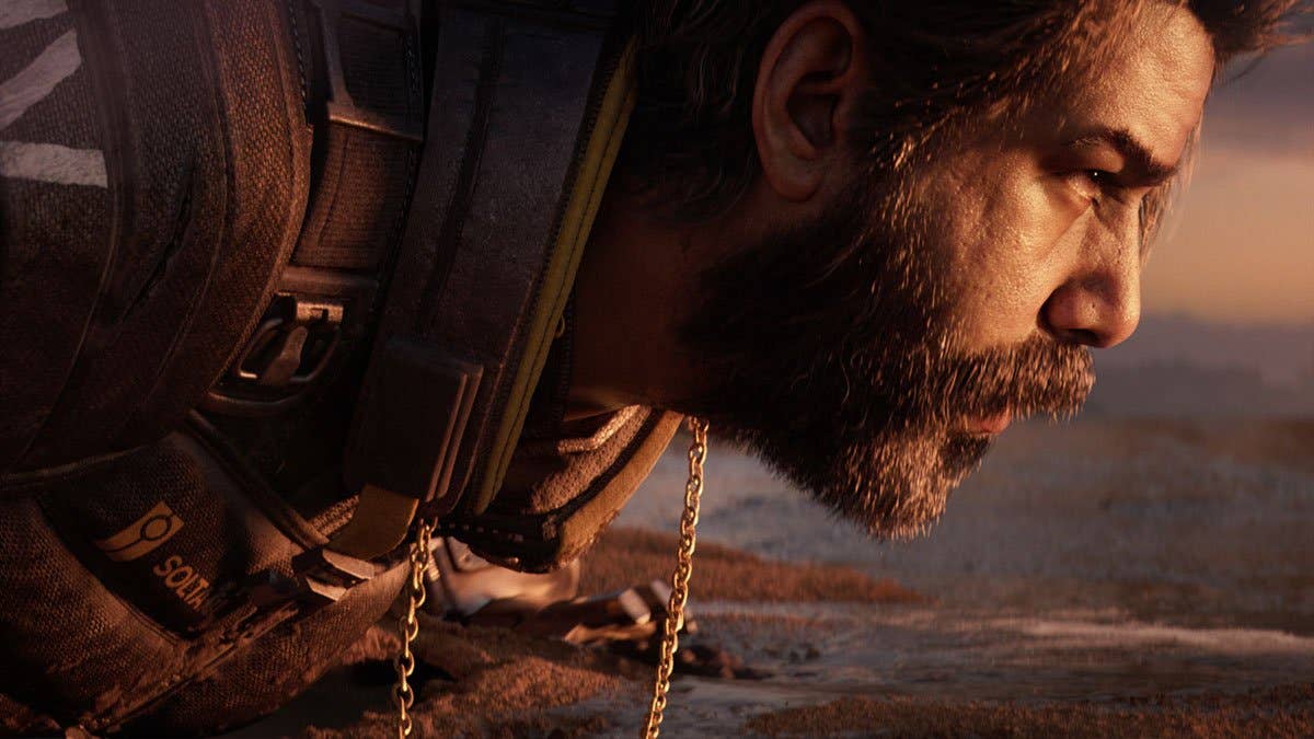 Saros screenshot showing a bearded man lying on a sandy beach. He is looking forward as waves lap towards him and he has a gold chain around his neck