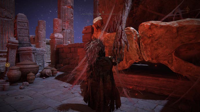 A warrior touches a giant withered arm in Elden Ring.