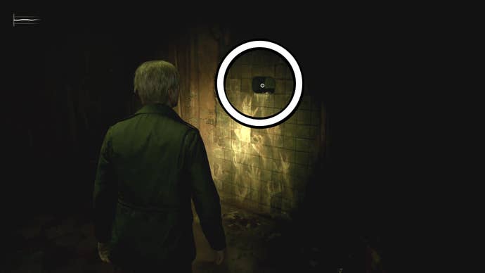 A white circle showing the location of the Key of Bliss key item inside a gap in a wall in Silent Hill 2.
