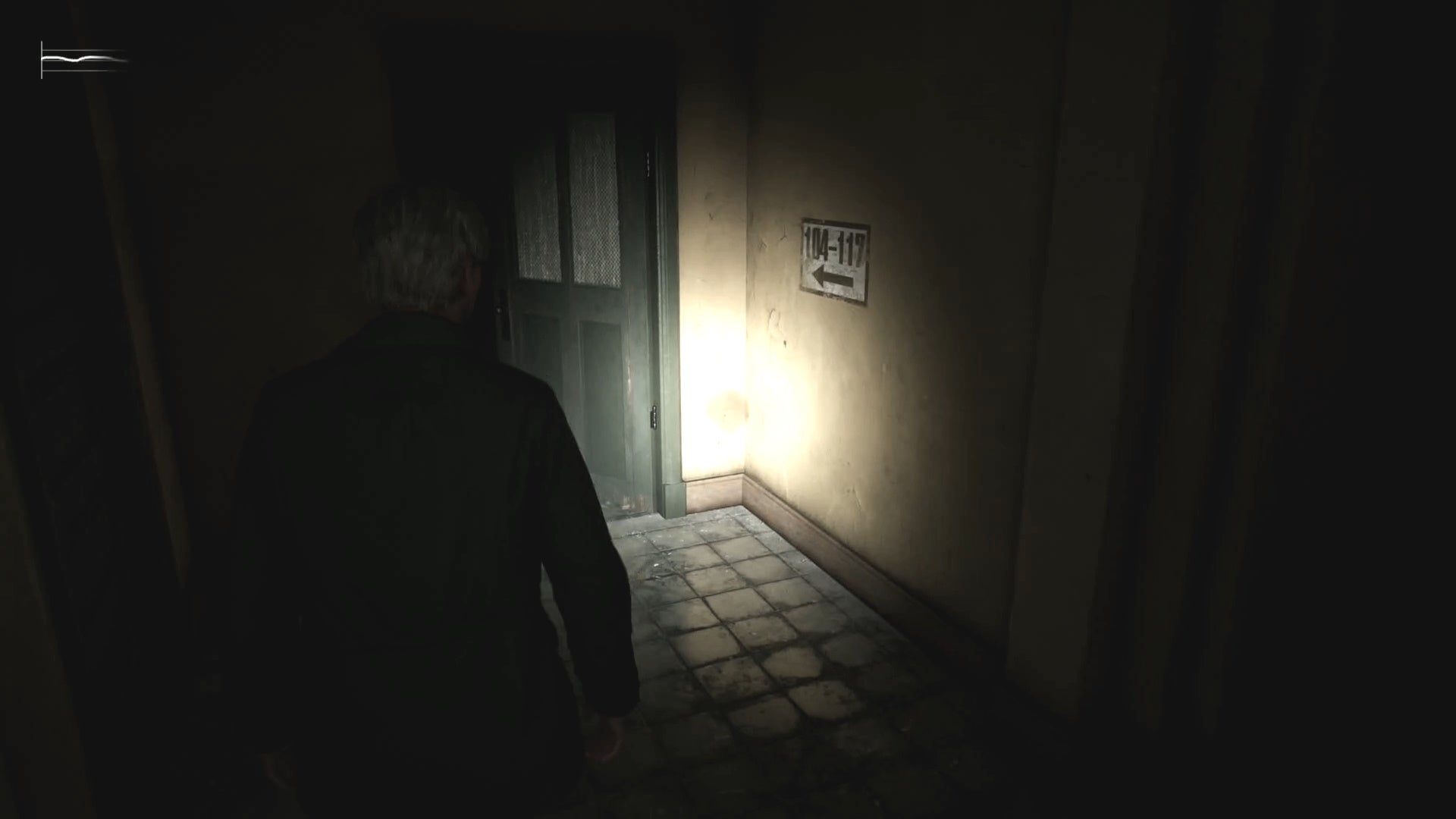 James looking at a sign pointing to rooms 104 - 117 on 1F of Wood Side Apartments in Silent Hill 2.