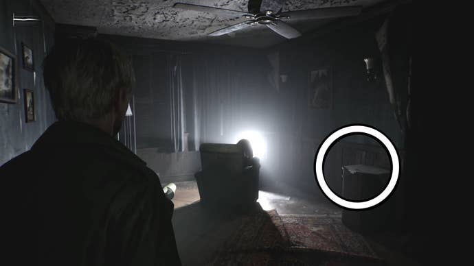 A white circle showing the Apartment 212 Key on a desk beside somebody watching a bright TV in Silent Hill 2.