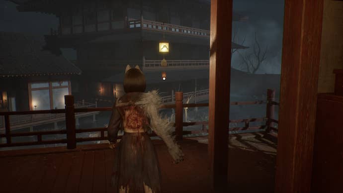 Hinako looks at a bell hanging from a tree with a mountain symbol on it in Silent Hill f