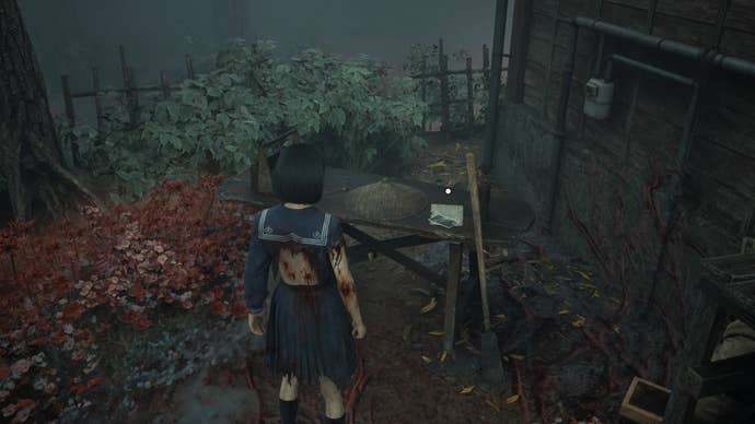 Hinako looks at the fifth Research Journal Photo on a workbench in Silent Hill f