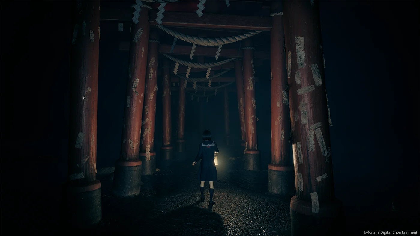 Hinako walks through a series of torii gates in the dark in Silent Hill f.