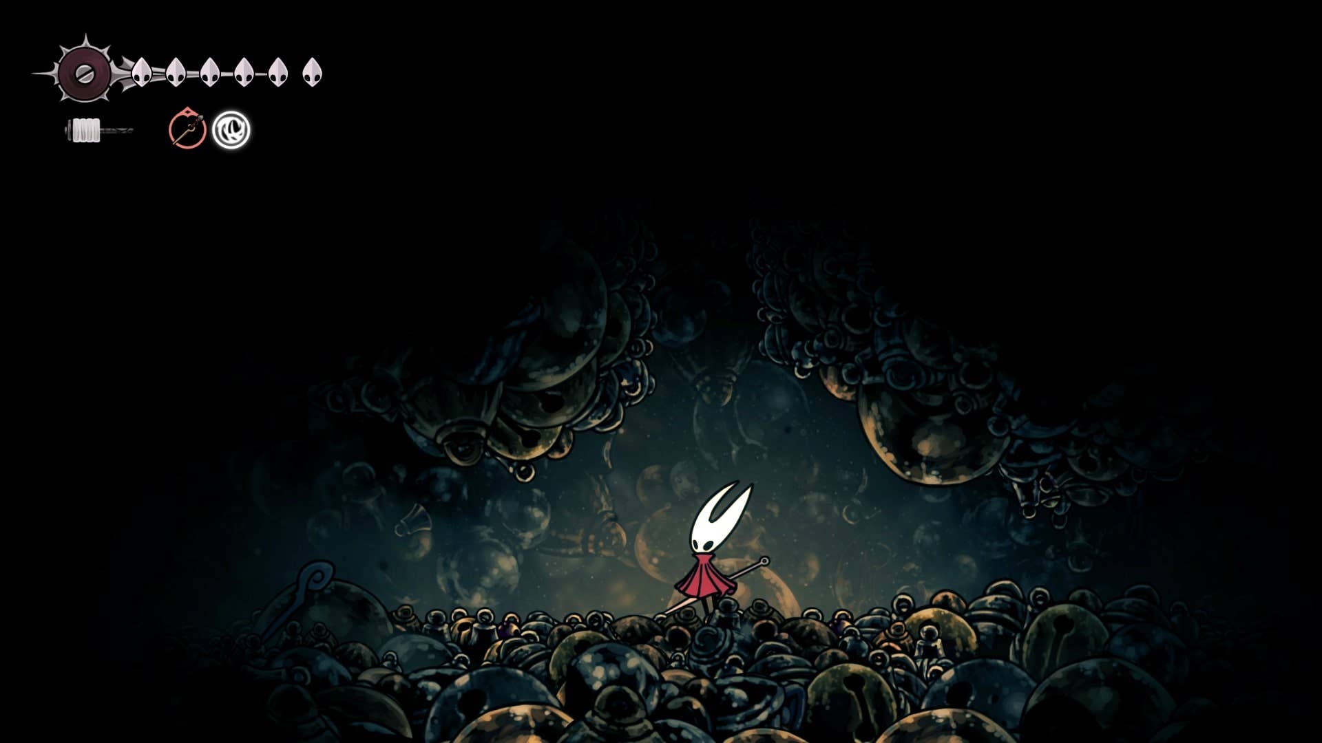 Hornet fica sob uma passagem estreita ao lado do sino eremita em Bellhart em Hollow Knight: Silksong