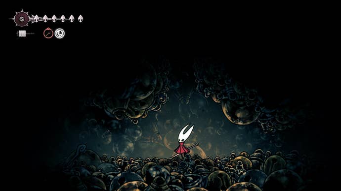Hornet stands beneath a narrow passage beside the Bell Hermit in Bellhart in Hollow Knight: Silksong