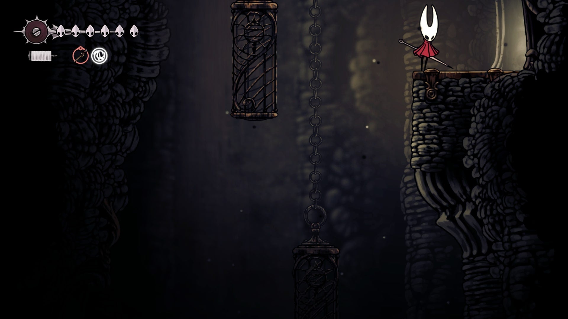 Hornet stands beside a hanging cage in Blasted Steps in Hollow Knight: Silksong