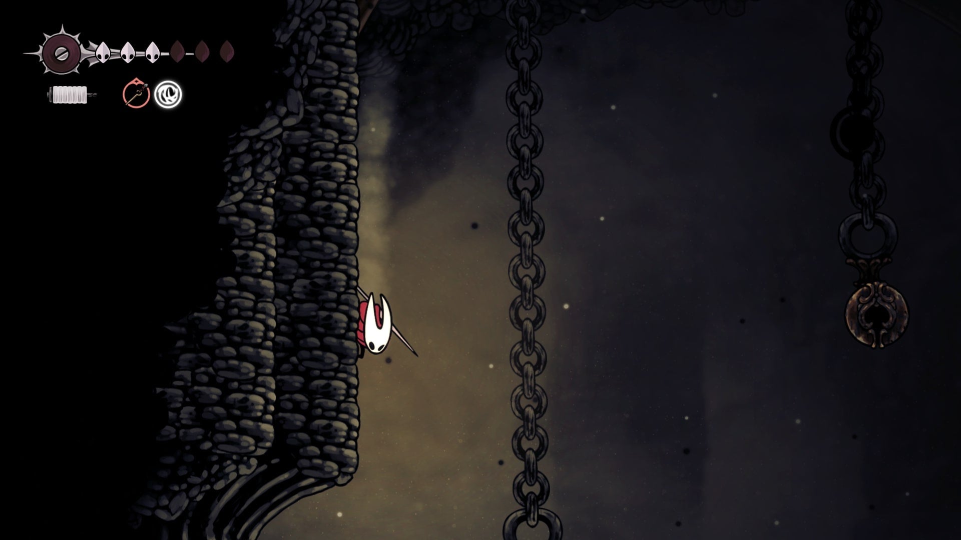 Hornet slides down a wall beside a bell in Blasted Steps in Hollow Knight: Silksong