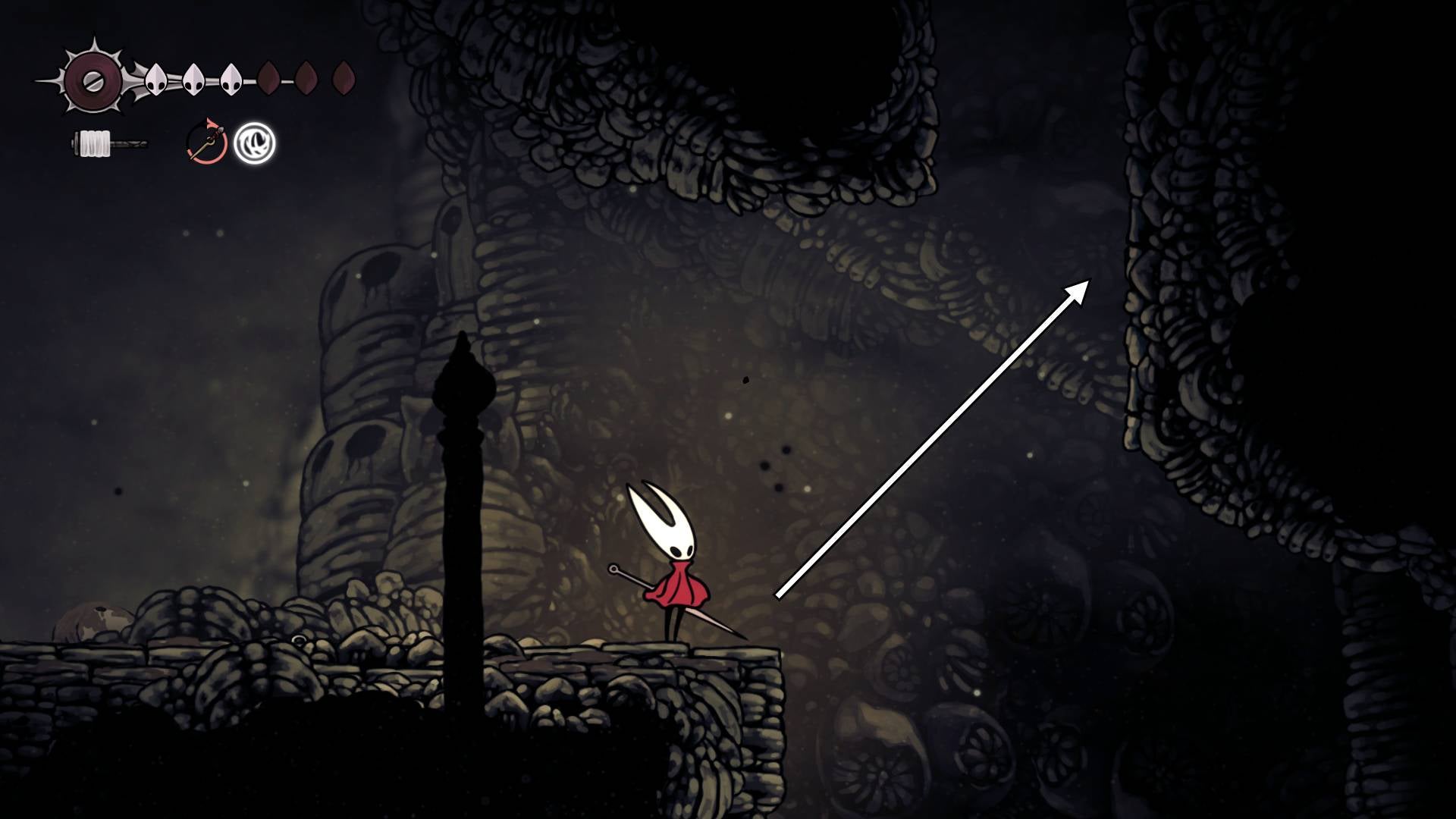 Hornet stands on a stone platform while looking up at a wall she can climb in Blasted Steps in Hollow Knight: Silksong