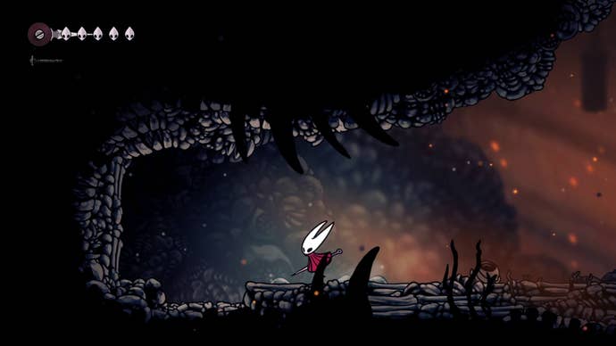 Hornet stands beside a section of rubble flooring that can be jumped down in Hollow Knight: Silksong