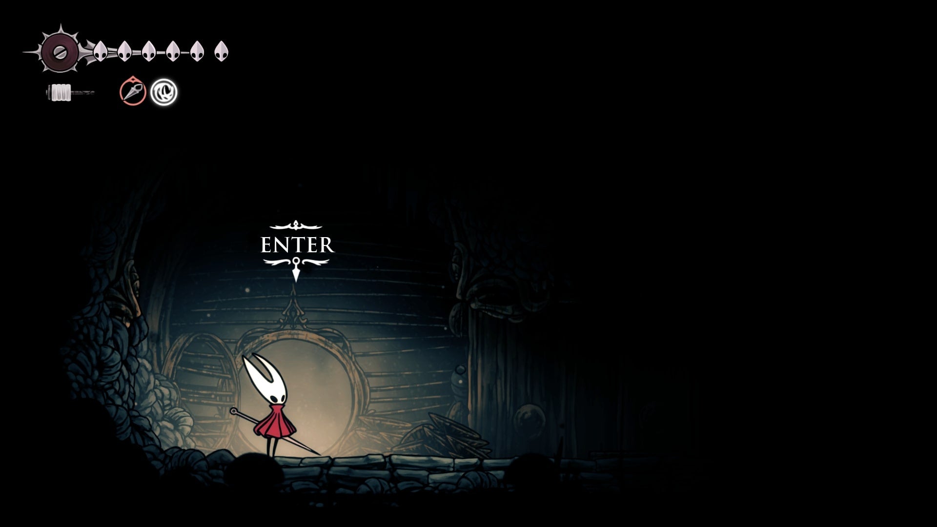 Hornet stands in front of a cave entrance in The Slab in Hollow Knight: Silksong