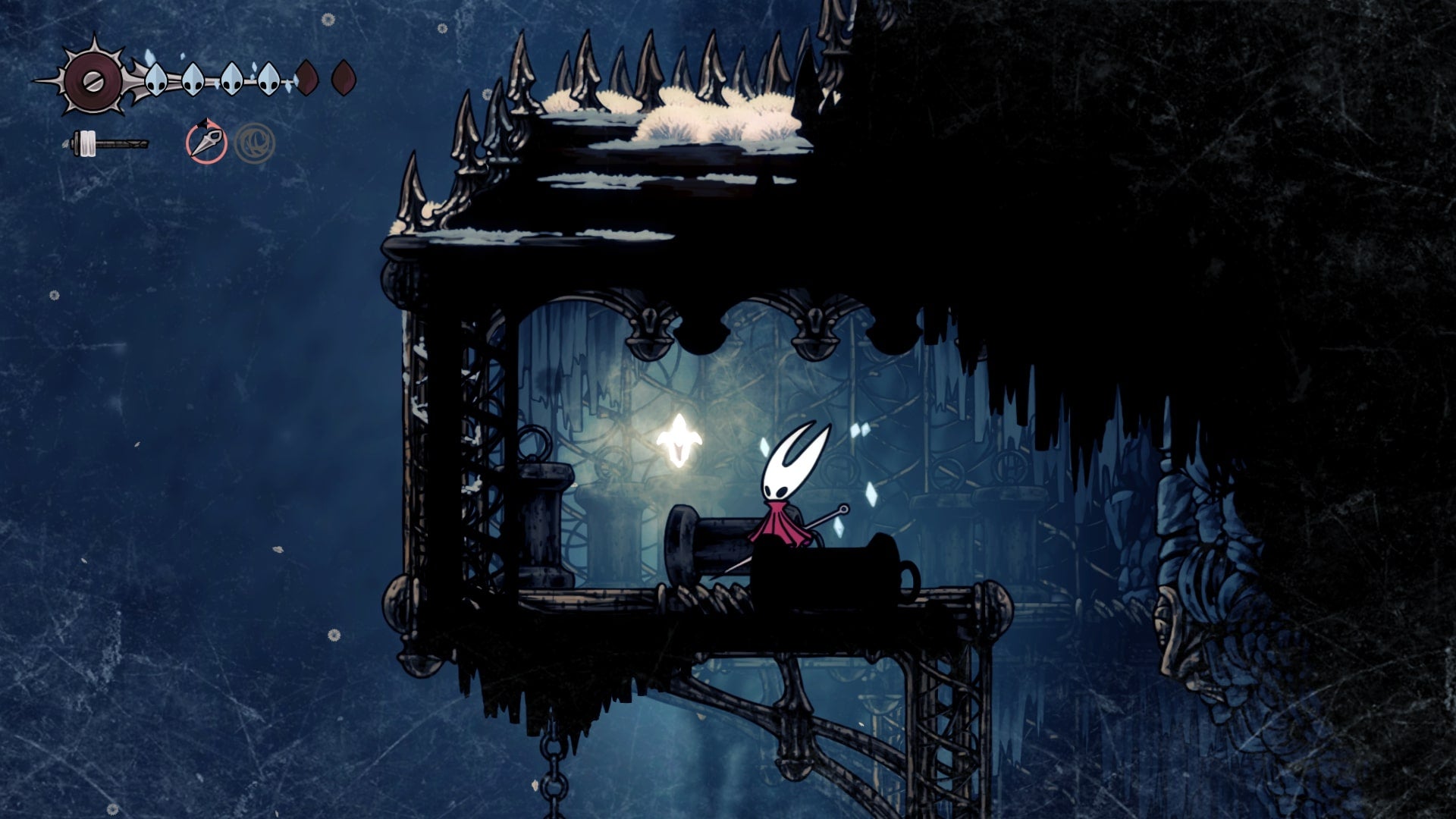 Hornet stands beside a Spool Fragment in The Slab in Hollow Knight: Silksong