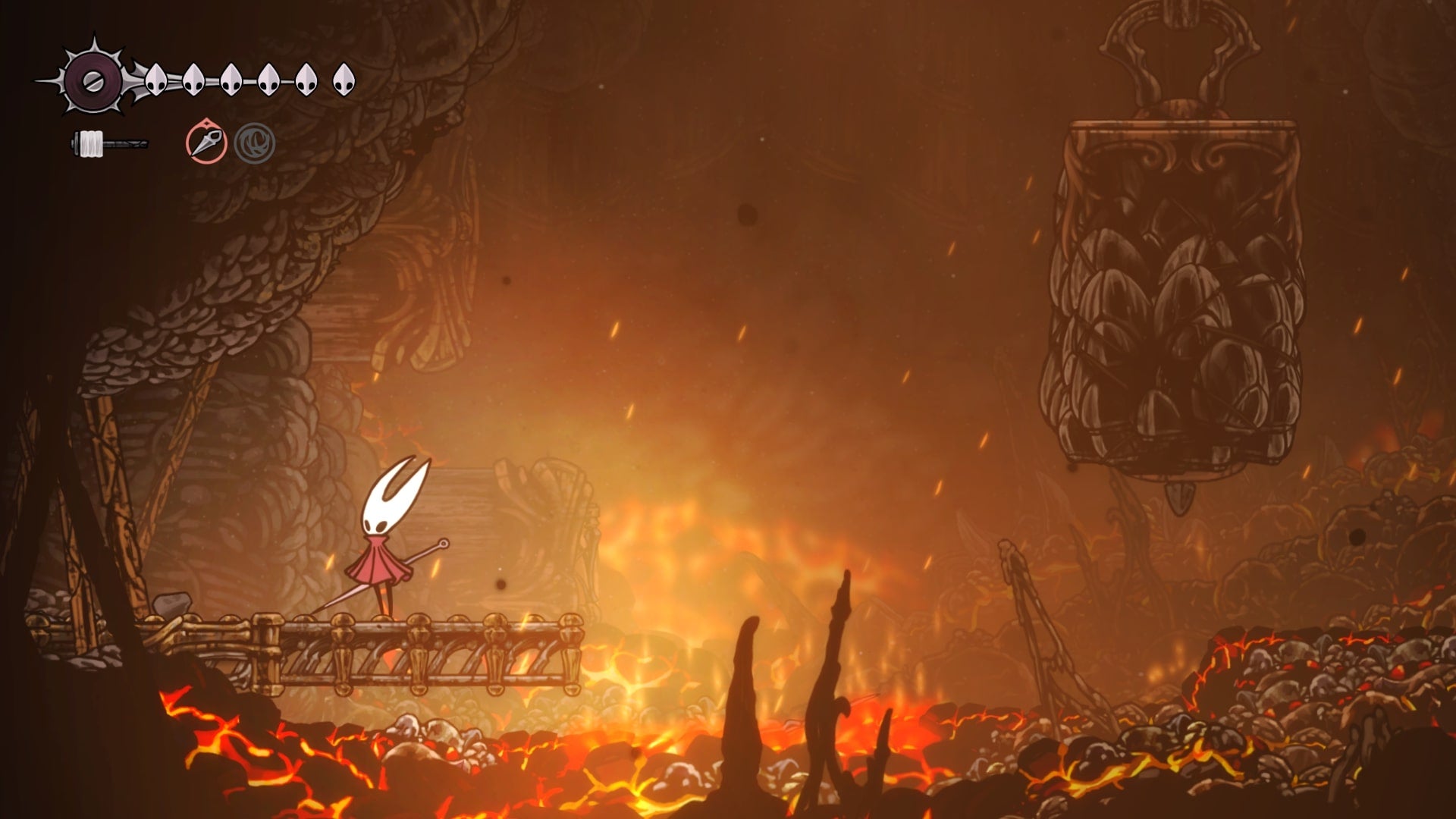 Hornet stands on a platform by a wooden barricade in the Underworks in Hollow Knight: Silksong