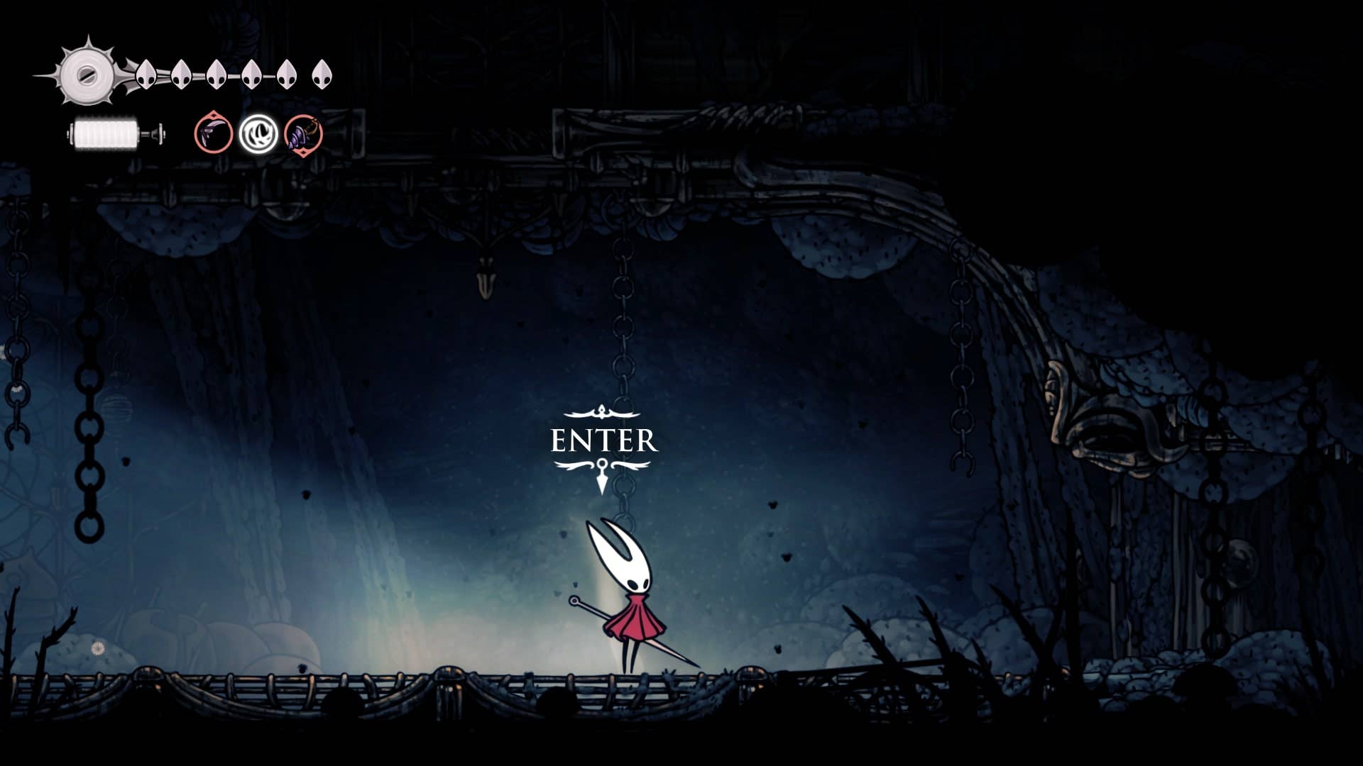 Hornet fica do lado de fora da entrada da arena da Mãe Lamentadora - a Mãe da Ninhada - em Hollow Knight: Silksong