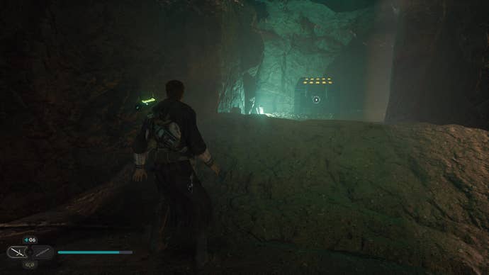 Star Wars Jedi Survivor screenshot showing Cal Kestis in a dark building, looking up at a rocky ledge that’s illuminated with green light.
