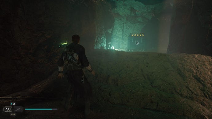 Star Wars Jedi Survivor screenshot showing Cal Kestis in a dark building, looking up at a rocky ledge that’s illuminated with green light.