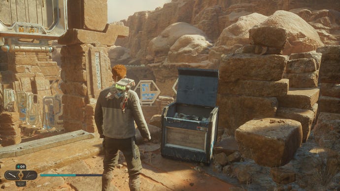 Star Wars Jedi Survivor screenshot showing Cal stood near a chest on a sandy ledge.
