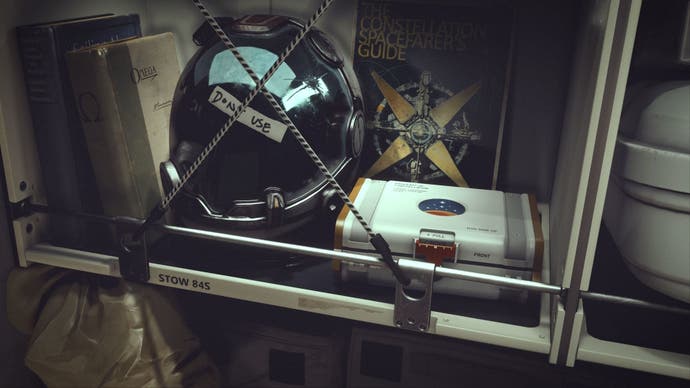 An astronaut helment with a note saying 'do not use' stuck on it beside a small white case on a book shelf.