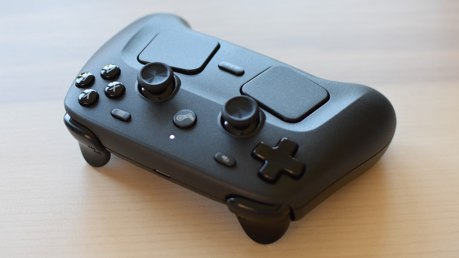 A Steam Controller, facing its shoulders buttons towards the camera, on a table.