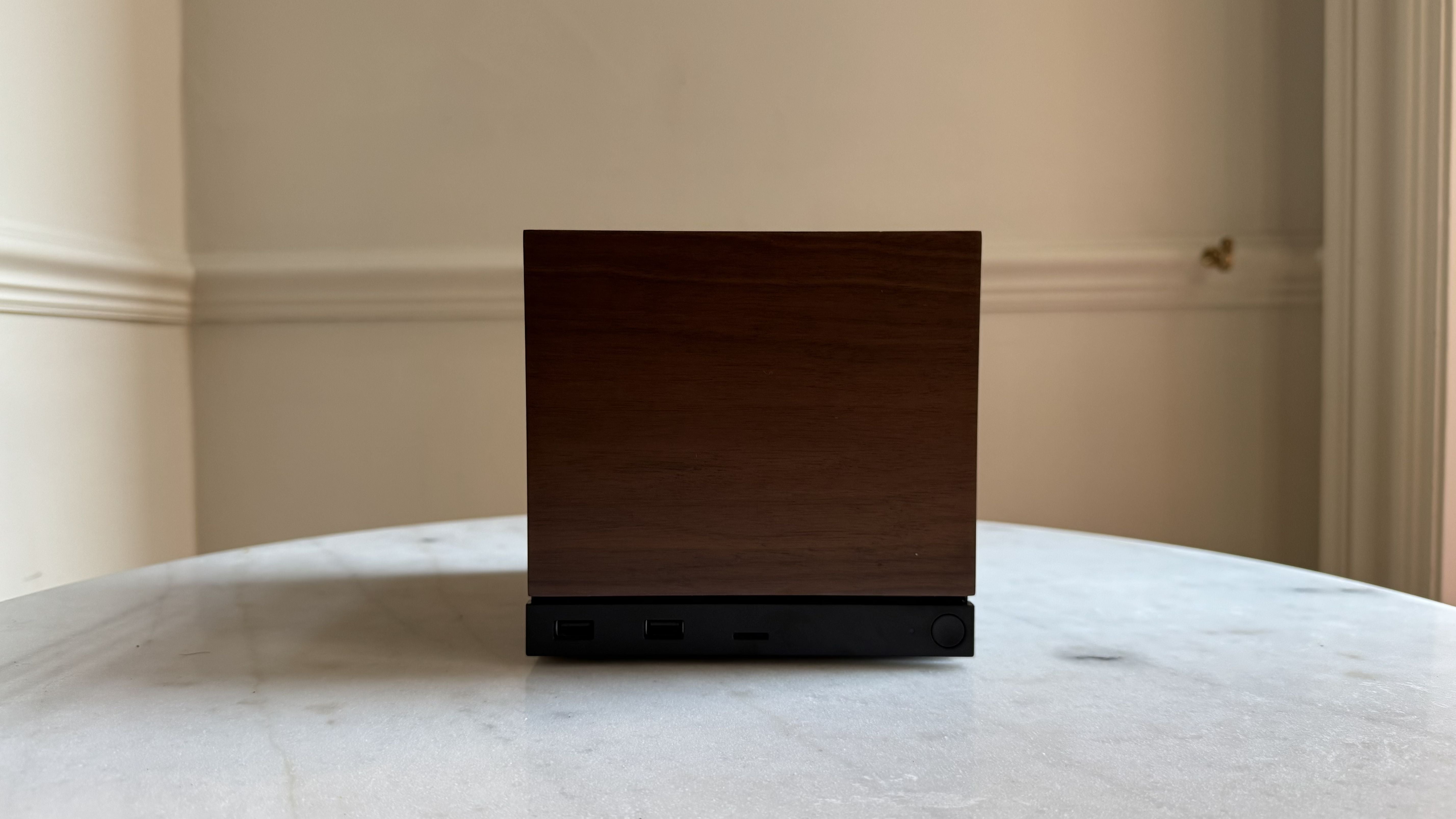 Steam Machine photograph showing the steam machine with wood faceplate on a marble circular table in front of a grey/beige wall