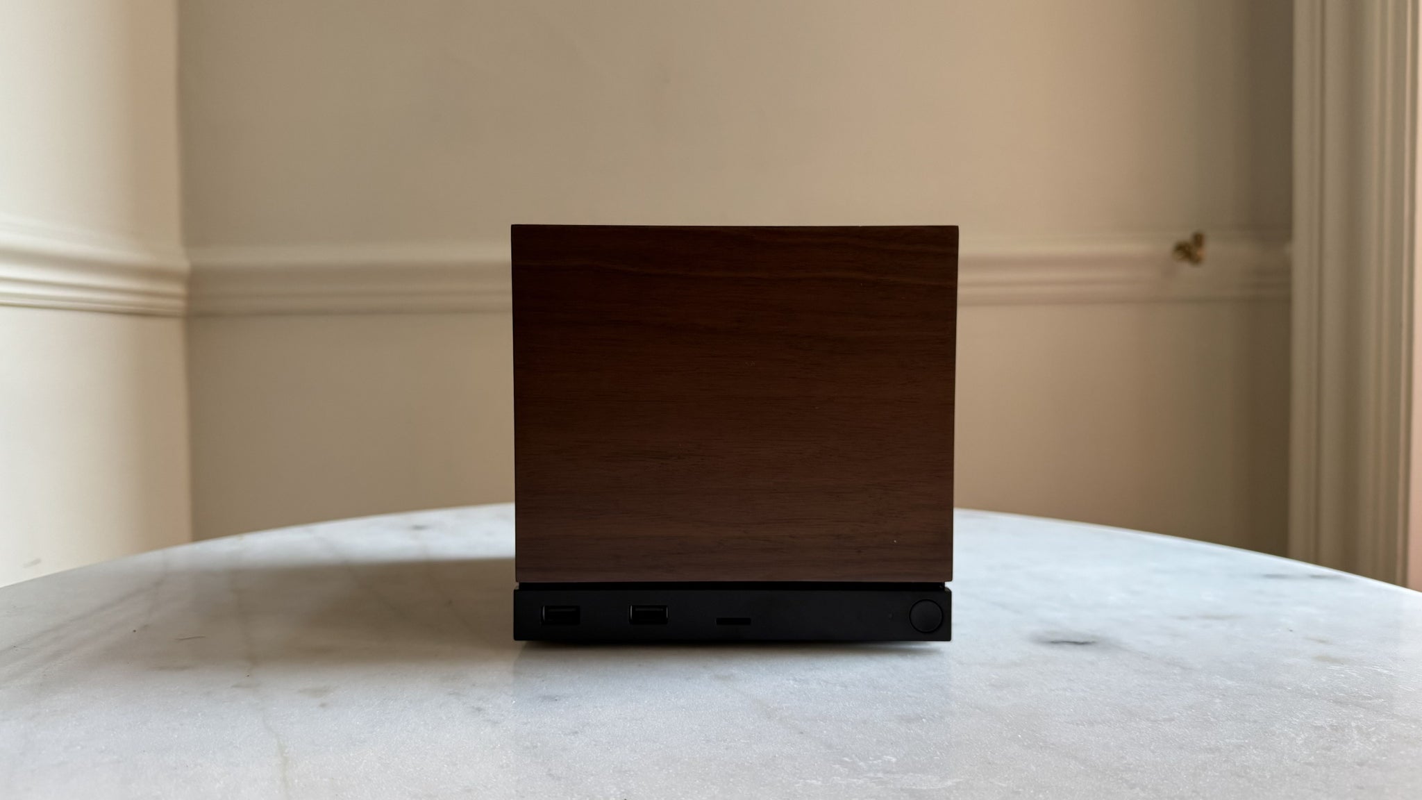 Steam Machine photograph showing the steam machine with wood faceplate on a marble circular table in front of a grey/beige wall