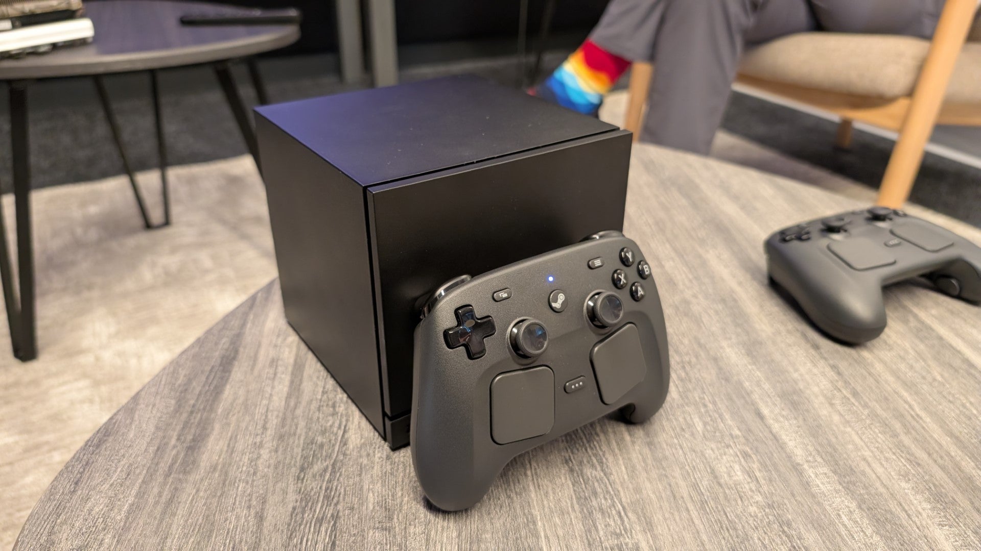 A 2026 Steam Machine with Valve's new Steam Controller propped up against it.