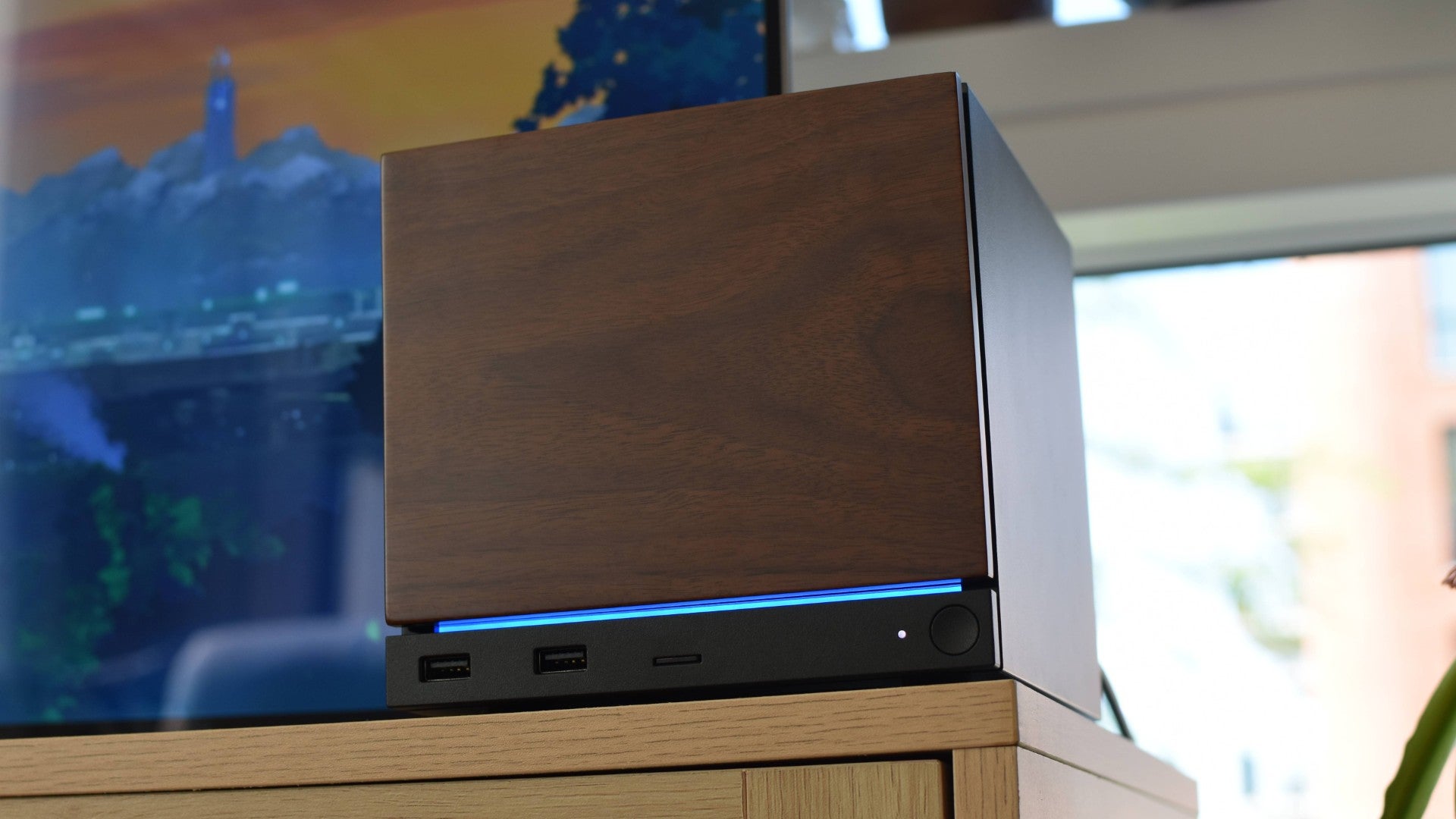 A Steam Machine with the optional wood panel next to a TV.
