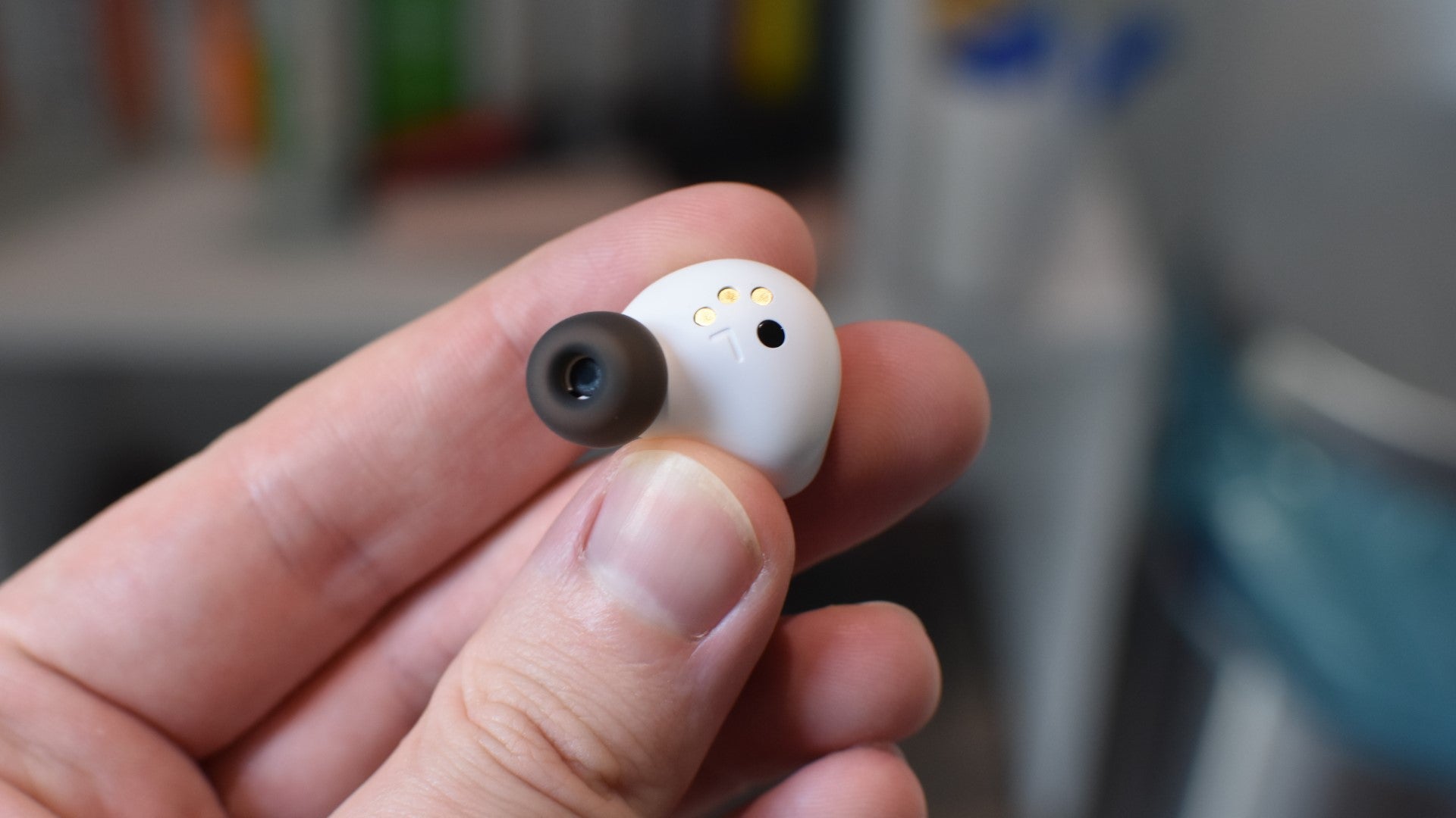 A single SteelSeries Arctis GameBud being held up between fingers. - 6