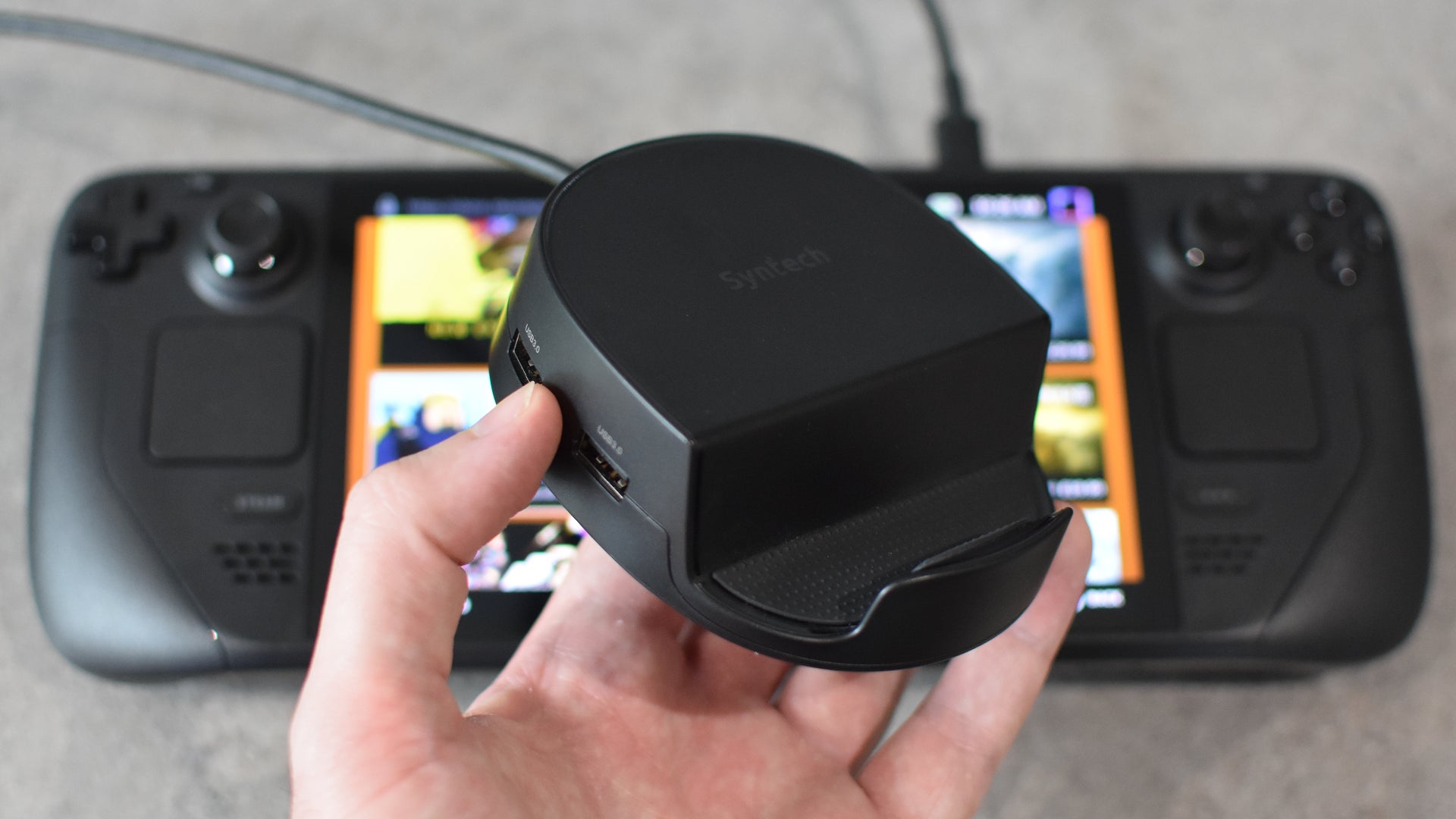 The Syntech Docking Station being held up in front of a Steam Deck OLED. - 5