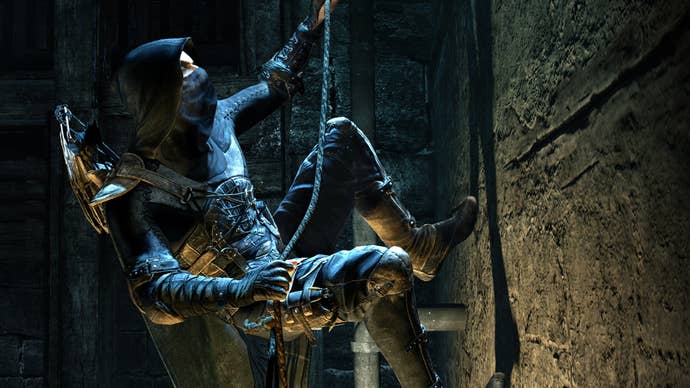 Garrett in 2014’s Thief reboot, climbing a wall on a rope. He’s wearing all black leather and is hooded.