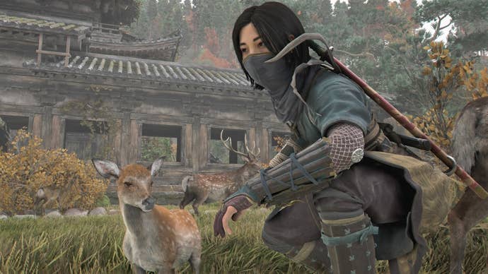 Naoe crouched beside a fawn in Assassin’s Creed Shadows.