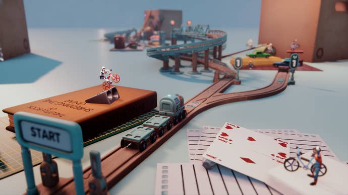 A small toy train track goes off into the distance, and around it, a variety of small figures stage a little bike stunt off playing cards and stacked books.