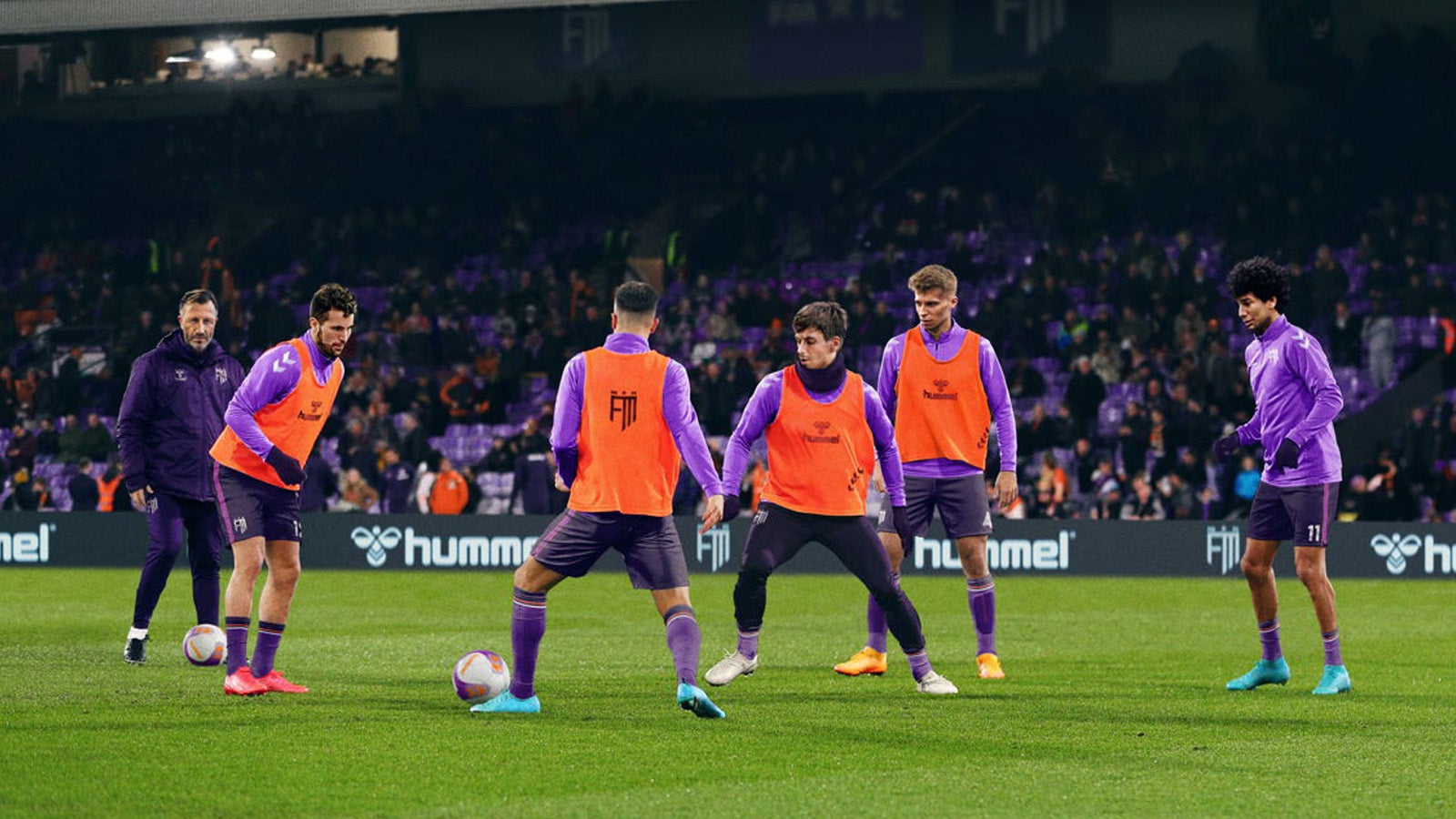 Football Manager 24 artwork showing a group of players training on a football field.