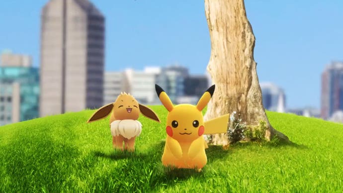 Pikachu and Eevee sit next to a tree on a hill, with a cityscape shown in the background.
