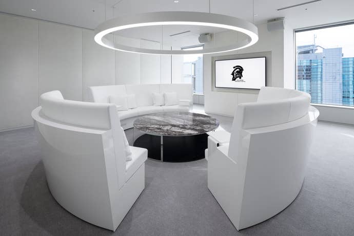 An all-white VIP meeting room in Kojima Productions with circular table and sofas