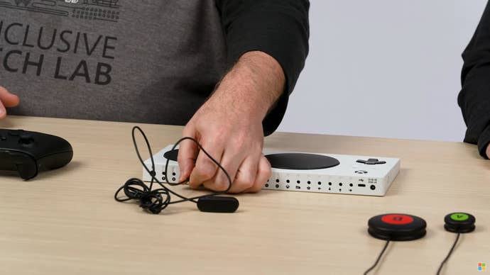 An a button being plugged into one of the 3.5mm ports on the back of an Xbox Adaptive Controller.