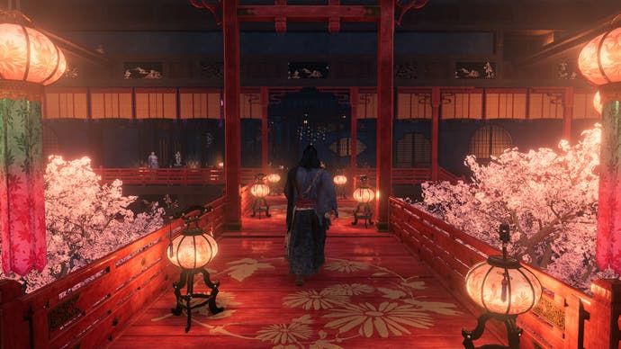 Captura de pantalla oficial de Rise of the Ronin que muestra al jugador caminando hacia la entrada de un edificio tradicional japonés de color rojo brillante y rosa.