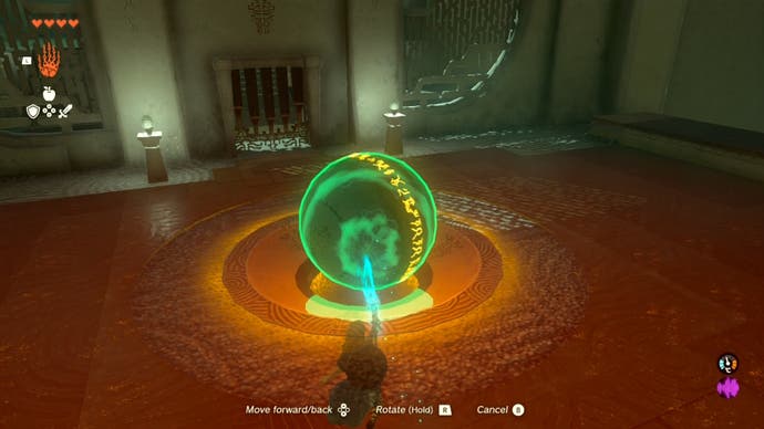 Link using his Ultrahand ability to move a large metal ball into a hole in the ground in the Runakit Shrine.