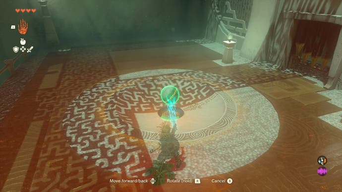 Link moving a small metal ball into a small hole in the ground at the Sinakawak Shrine in The Legend of Zelda: Tears of the Kingdom.