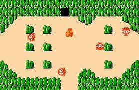 Link faces off against several enemies in a sandy stretch of land surrounded by green mountains. There’s a cave entrance at the top of the screen.